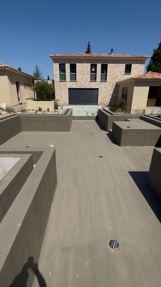 Maison presque terminée avec façade en pierre, piscine en construction au premier plan, réalisation AGM